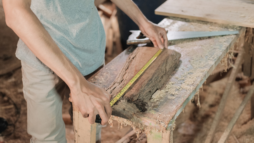 Close up Carpenter's Hand Measuring Wood Using Carpenters Ribbon Ruler