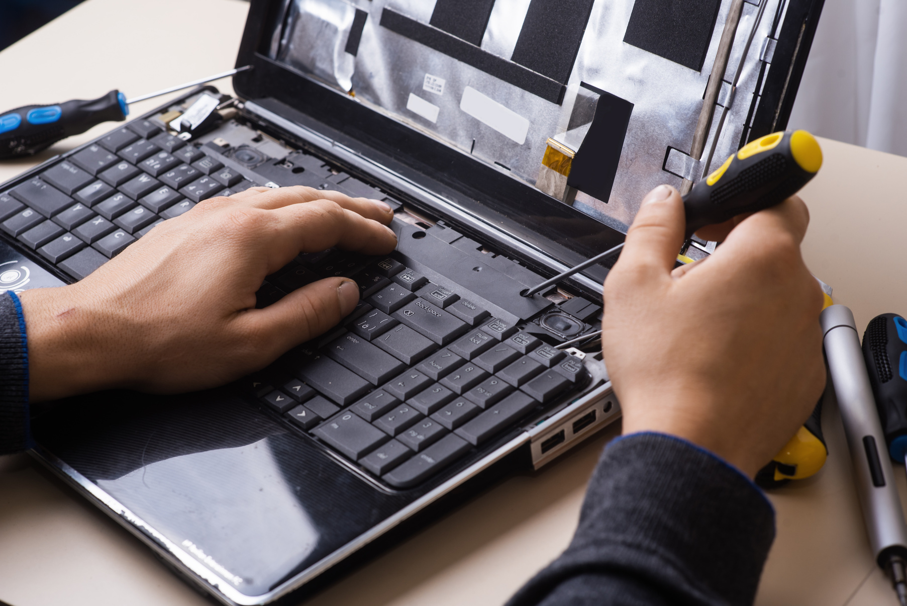 Wizard repairs laptop with tools and hands