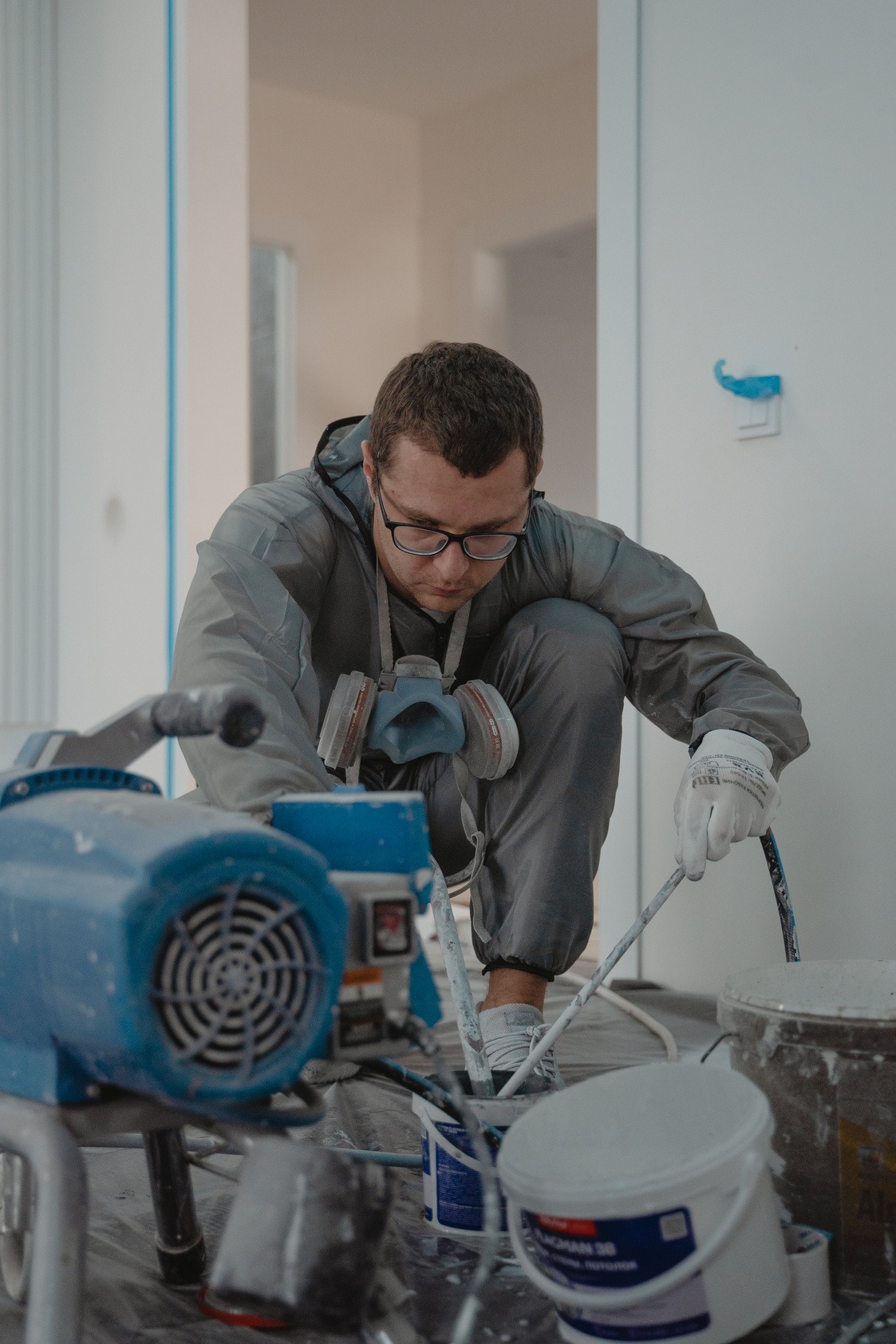 A Man in Gray Suit Painting a House